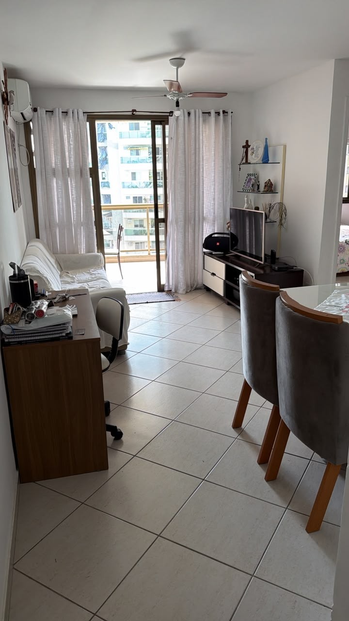 Sala do apartamento mobiliado na Rua Aroazes, com sofá branco, TV, ar-condicionado e porta de vidro para a varanda com vista dos prédios