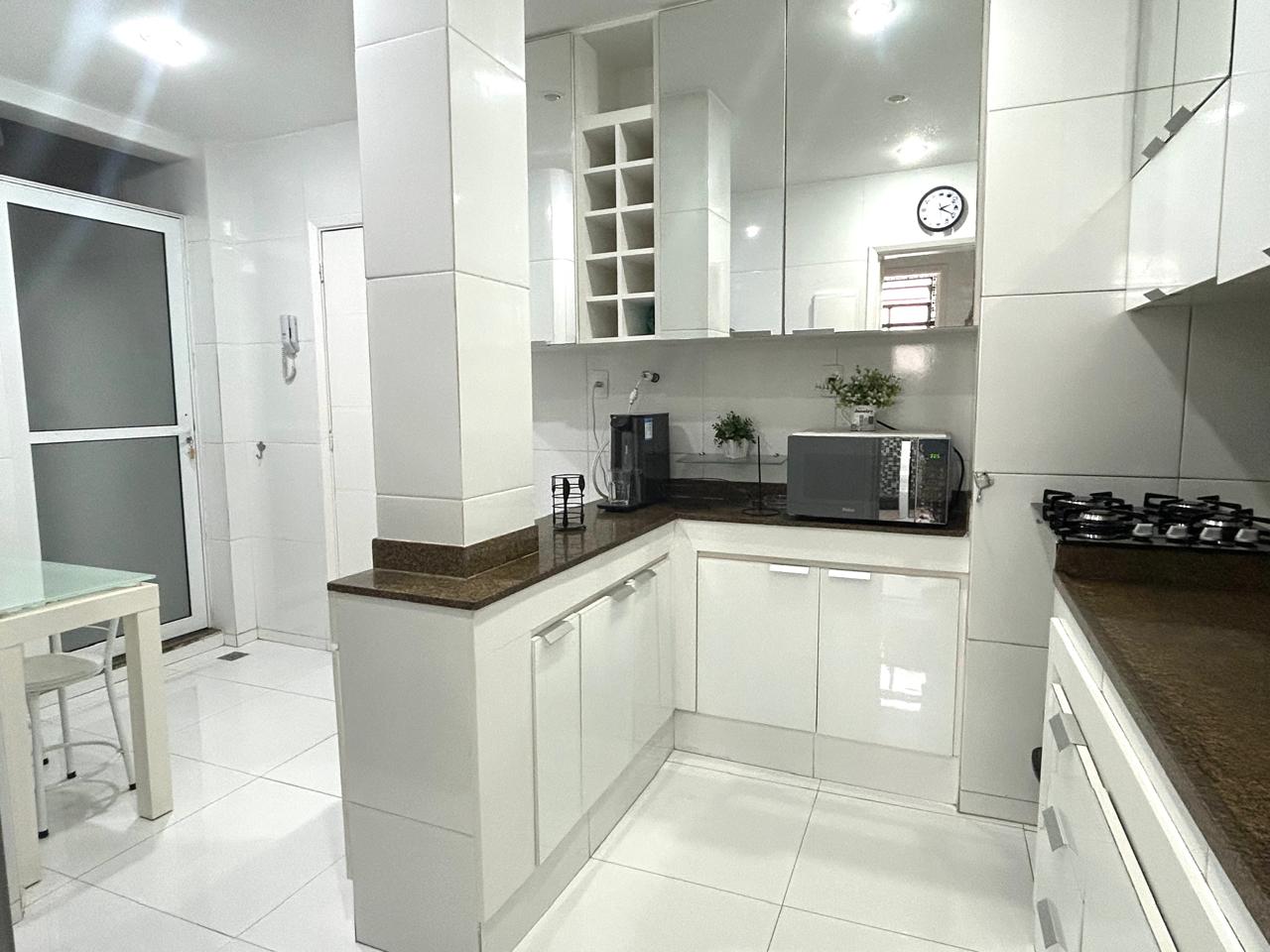 Copa-cozinha planejada do apartamento em Ipanema, com armários brancos e bancada de granito